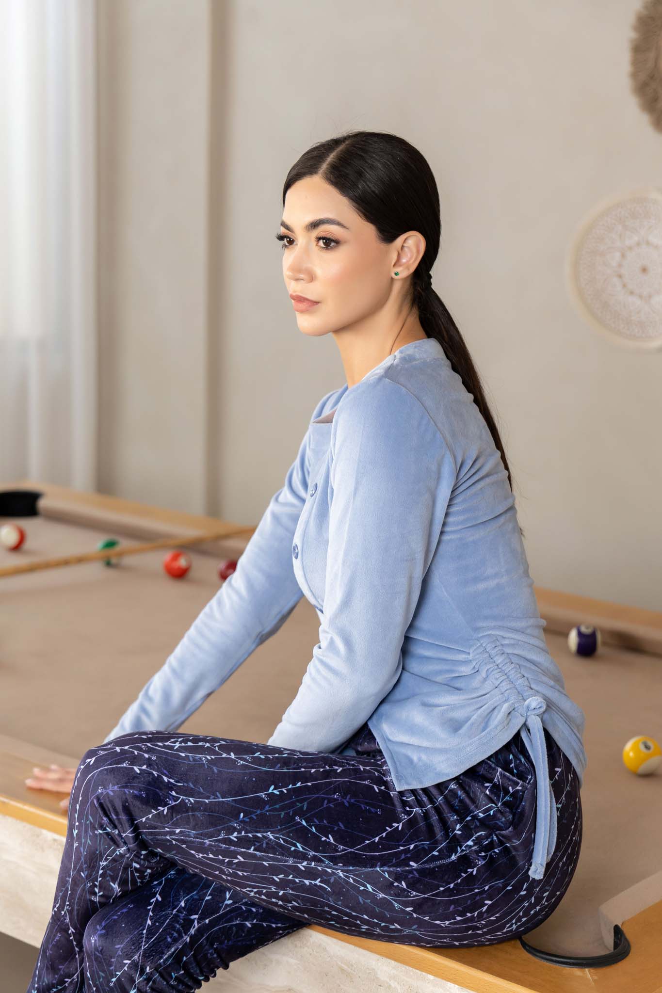 بلوزة زرقاء ناعمة بتفاصيل أزرار وبنطلون مريح بنمط تجريدي داكن.