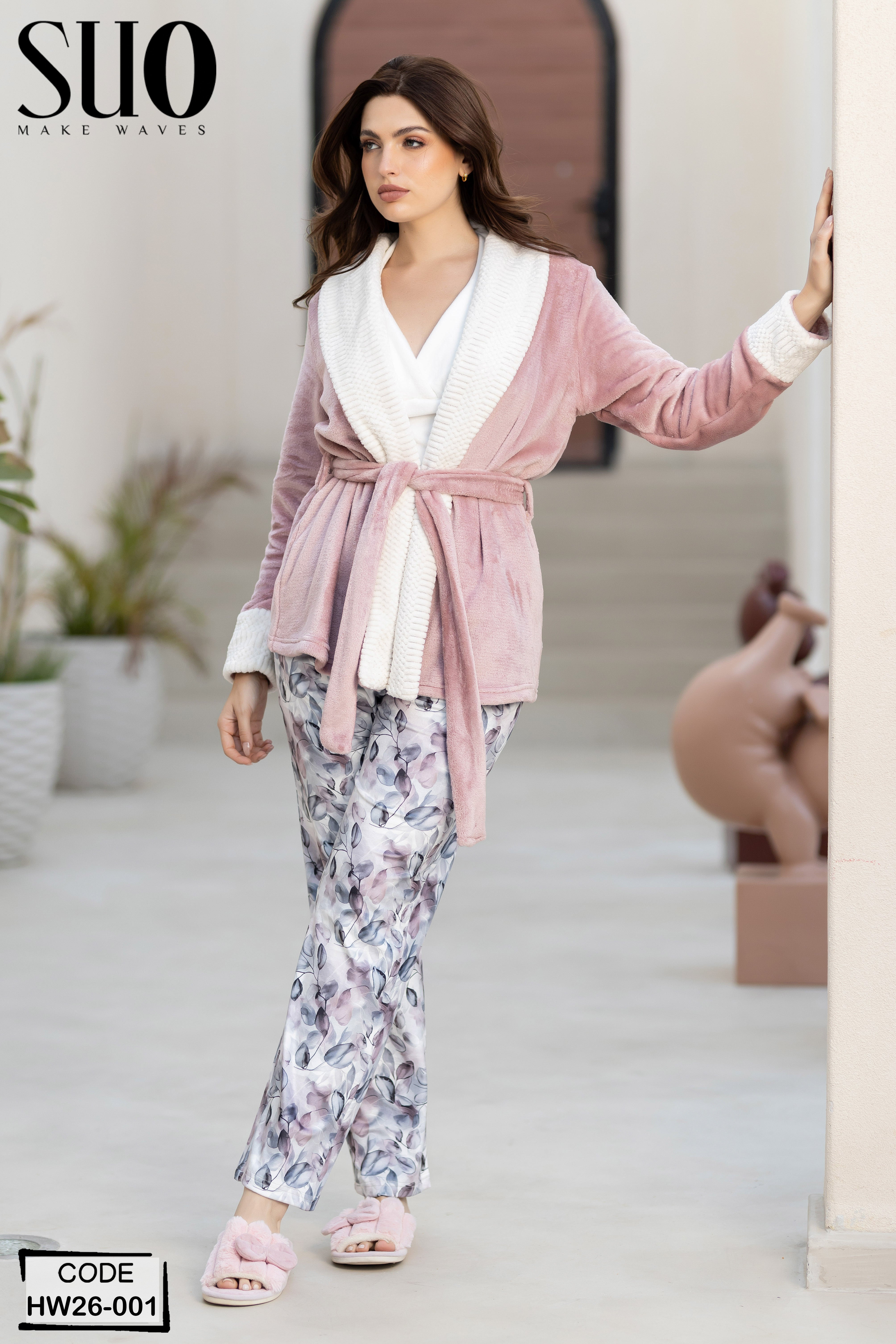 Woman wearing a pink robe and floral pants in an outdoor setting