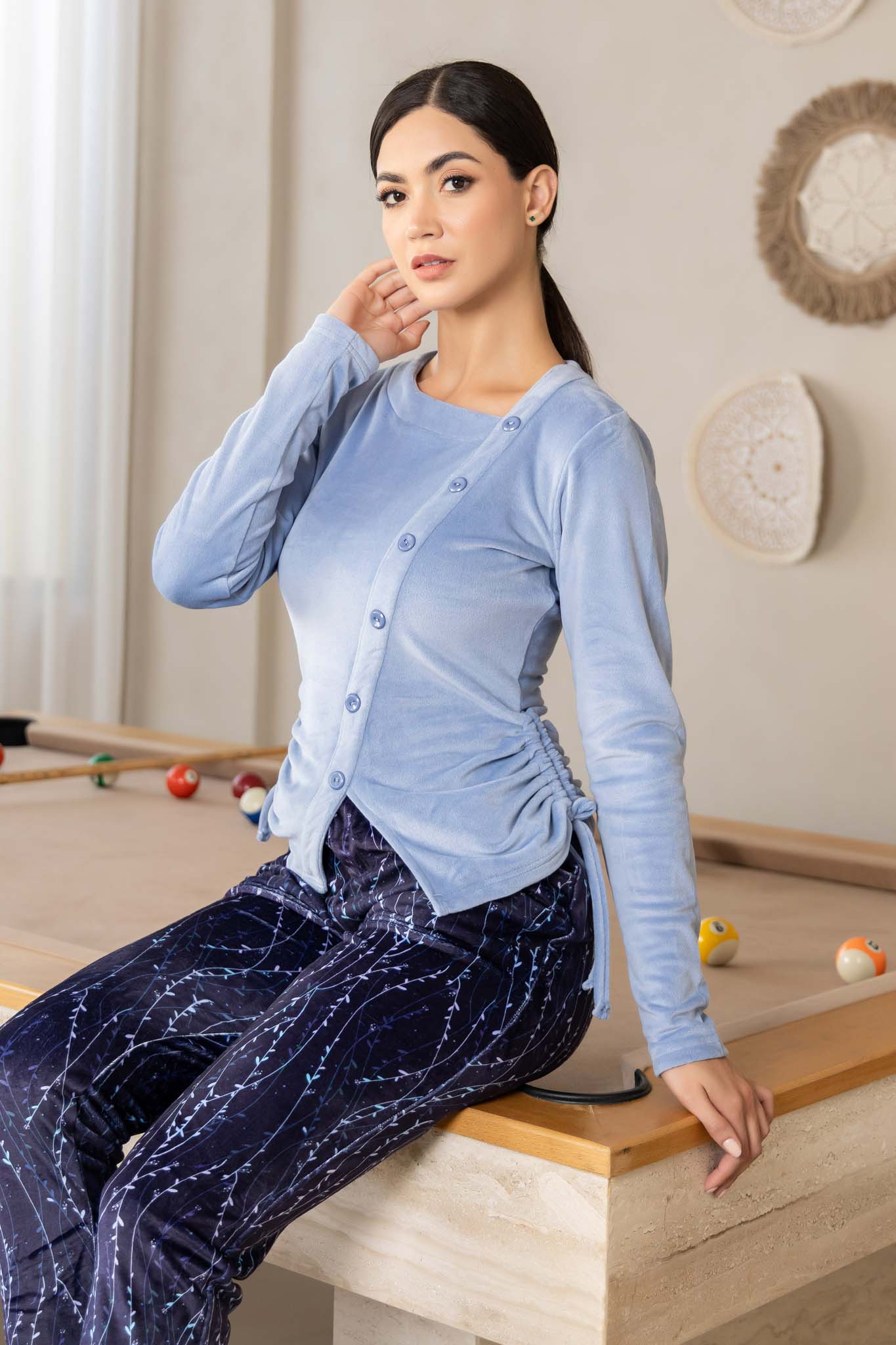 بلوزة زرقاء ناعمة بتفاصيل أزرار وبنطلون مريح بنمط تجريدي داكن.